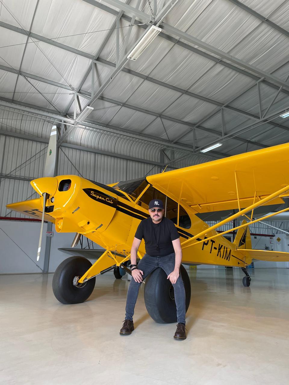 Orlandinho Custódio em frente a um avião amarelo